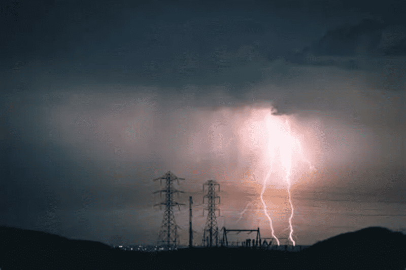 A powerful lightning strike hitting near a power line and substation